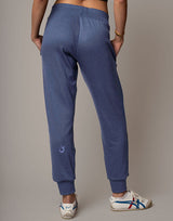 Person wearing blue sweatpants with a small logo on a plain background