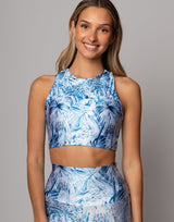 Woman wearing a blue floral sports bra and leggings on a gray background