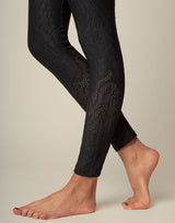 woman wearing chic black animal printed legging on grey background