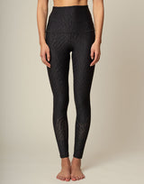 woman wearing chic black animal printed legging on grey background