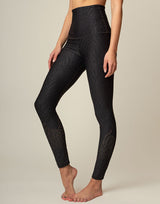 woman wearing chic black animal printed legging on grey background