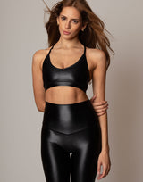 Woman wearing a black sports bra and leggings against a neutral background