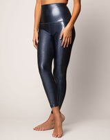 woman wearing high shine and sparkling navy colored legging on grey background