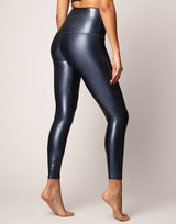 woman wearing high shine and sparkling navy colored legging on grey background