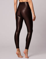 woman wearing high shine and sparkling chocolate brown colored legging on grey background