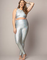 woman wearing sneaker length legging with mermaid pattern of crystal blue colored sparkling fish scales on grey background