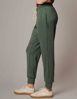 Green jogger pants worn by a person on a gray background