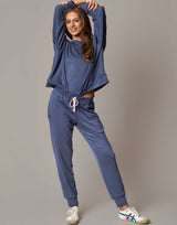 Woman wearing a blue tracksuit with white sneakers on a plain background