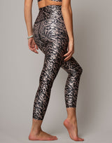 Person wearing black and silver patterned leggings on a plain background