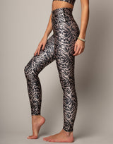 Person wearing black and white patterned leggings on a plain background