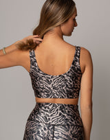 Woman wearing a patterned sports bra and leggings on a plain background