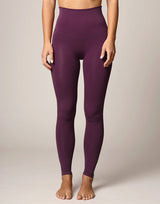woman wearing eggplant purple colored leggings on grey background