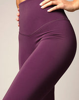 woman wearing eggplant purple colored leggings on grey background