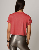 Person wearing a red crop top and shiny leggings on a plain background