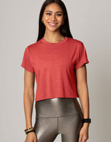 Woman wearing a red crop top and silver leggings on a plain background