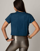 woman wearing teal colored t-shirt on grey background