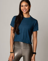 woman wearing teal colored t-shirt on grey background