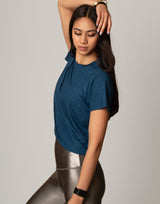 woman wearing teal colored t-shirt on grey background