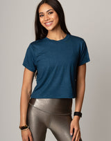 woman wearing teal colored t-shirt on grey background