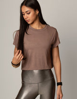 woman wearing toffee colored t-shirt on grey background