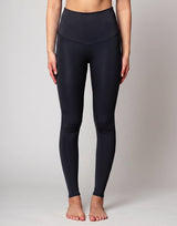 A model from the waist down wearing high-waisted, full-length athletic leggings in a solid dark navy color, standing against a light gray studio background.