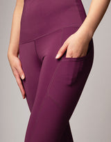 woman wearing violet legging with side pockets on grey background