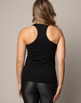 Person wearing a black tank top and black leggings against a neutral background