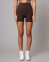 woman wearing chocolate brown colored shorts on grey background