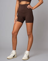 woman wearing chocolate brown colored shorts on grey background