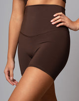 woman wearing chocolate brown colored shorts on grey background