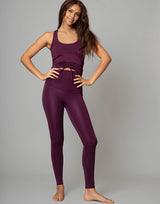 woman wearing eggplant purple colored tank top on grey background