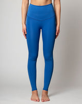 woman wearing azure blue colored legging on grey background