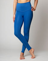 woman wearing azure blue colored legging on grey background