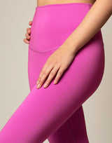 woman wearing orchid pink colored legging on grey background