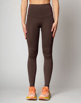 woman wearing chocolate brown colored legging on grey background