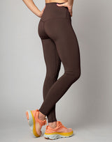 woman wearing chocolate brown colored legging on grey background