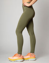 woman wearing moss green colored legging on grey background