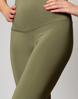 woman wearing moss green colored legging on grey background