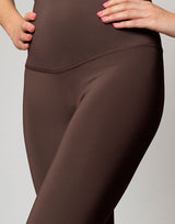 woman wearing chocolate brown colored legging on grey background