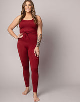 woman wearing tank top and legging set in cranberry red on grey background