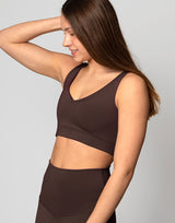 woman wearing chocolate brown colored v neck crop top on grey background