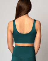 Person wearing a green sports bra and leggings set on a plain background