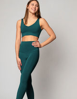 Woman wearing a green sports bra and leggings set on a gray background