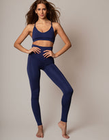 Woman wearing a blue sports bra and leggings on a plain background