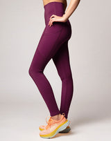 woman wearing violet legging with side pockets on grey background