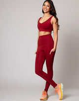 woman wearing v neck crop and legging set in cranberry red on grey background