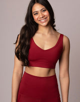 woman wearing v neck crop in cranberry red on grey background