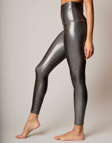 Person wearing shiny silver leggings on a plain background