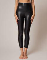 Person wearing black shiny leggings on a neutral background