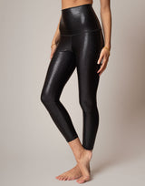 Black shimmer leggings worn by a person on a neutral background